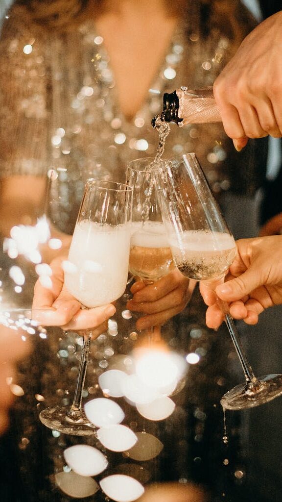 Person Pouring Champagne on Champagne Flutes
