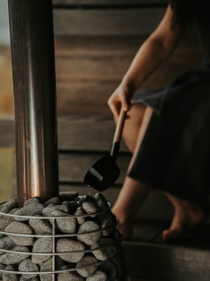Pouring Water Over Stones of Sauna Heater